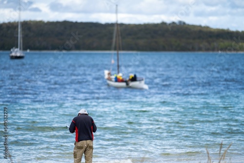 man watching wooden boat on the water, at the wooden boat festival in hobart tasmania australia