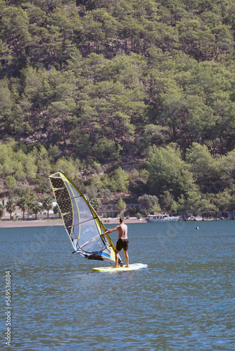 Man on a windsurf in the sea. Man learning to windsurf in the bay. Windsurfing.