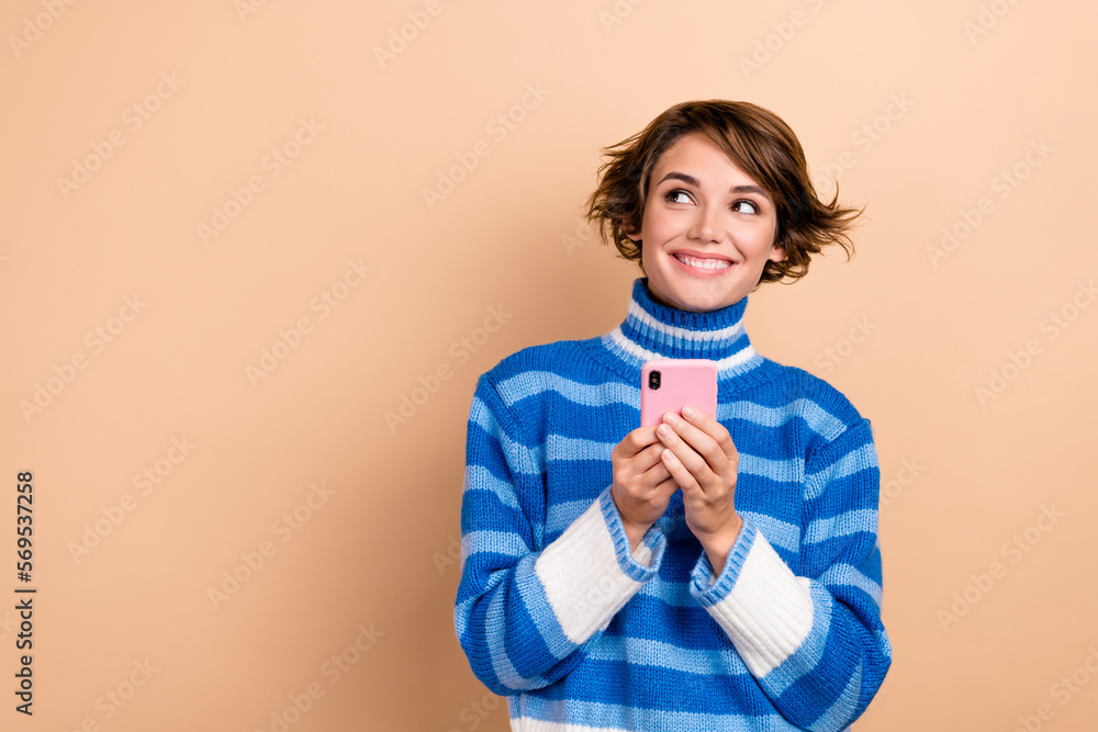 Photo of pretty cute lady wear striped knitted stylish clothes look empty space dream buy new gadget isolated on beige color background Photo of pretty cute lady wear striped knitted stylish clothes look empty space dream buy new gadget isolated on beige color background
