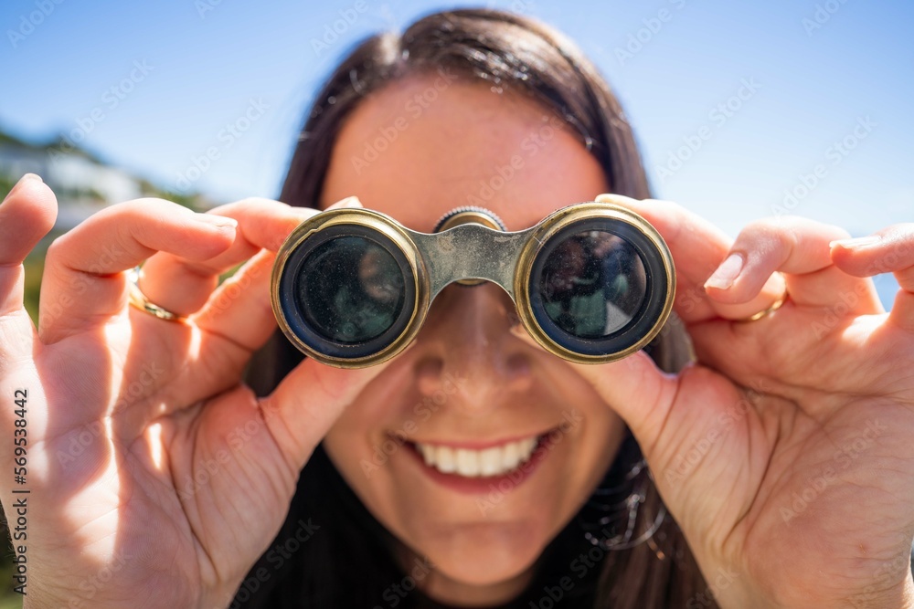 Girl using binoculars on a balcony in a city next to the sea, seaside town Girl using binoculars on a balcony in a city next to the sea, seaside town