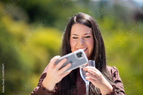 Girl video calling her friends on a zoom call. Woman on holiday skyping her family outside in a beautiful place photo