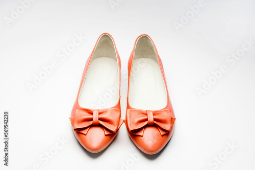 A pair of women's leather shoes with a bow tie, red, without heels, lie horizontally on one, on a white background. close distance