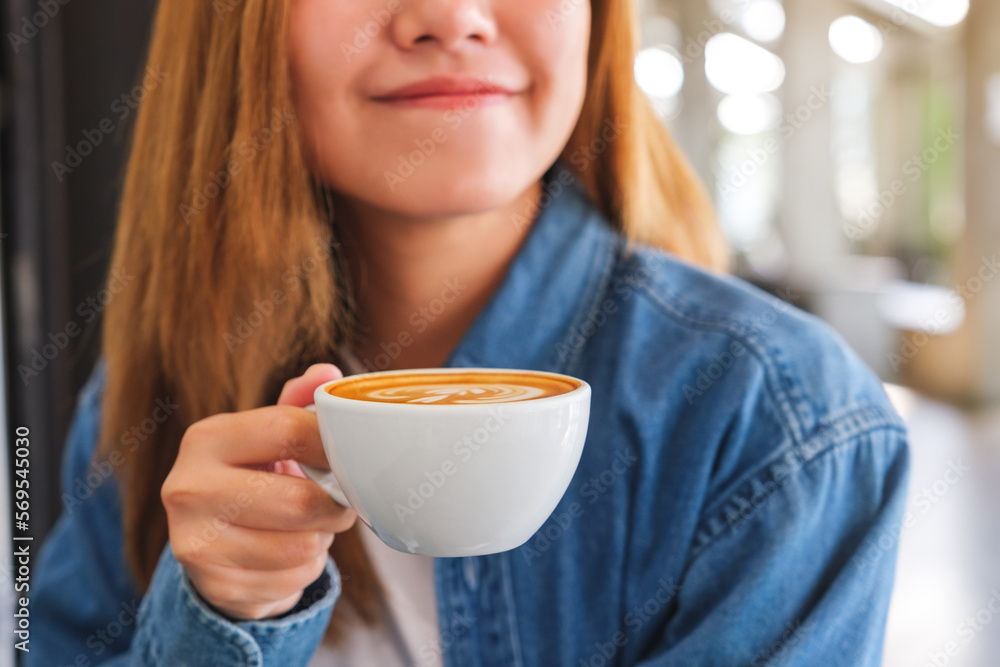 Closeup image of a young woman holding and drinking hot coffee in cafe Closeup image of a young woman holding and drinking hot coffee in cafe