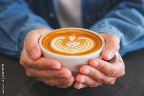 Closeup image of a woman holding coffee cup on the table