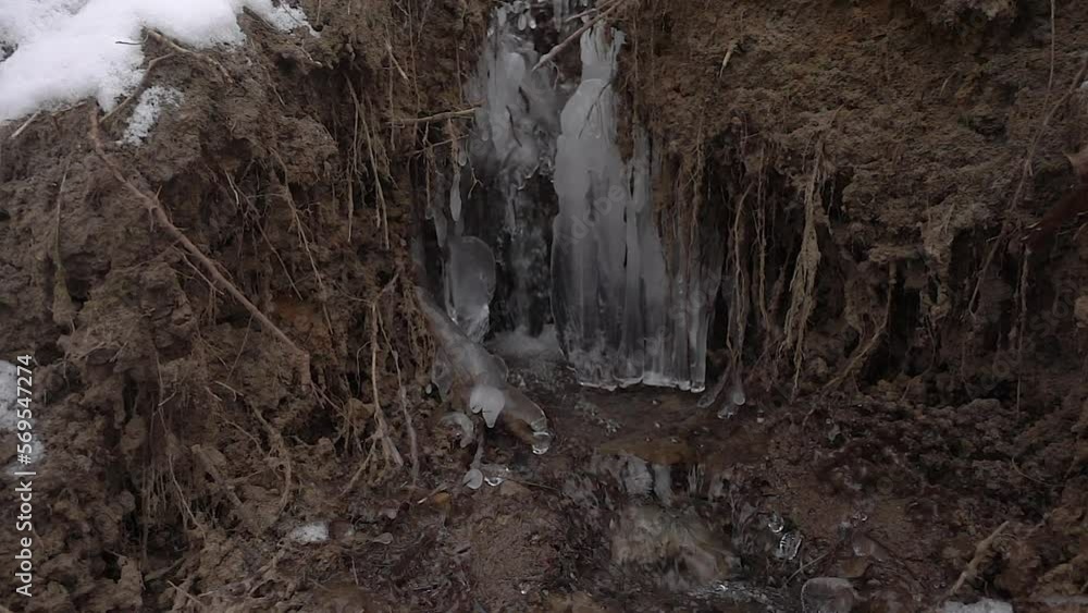 A stream of melt water flows along the slope of the forest along the ice icicles like a waterfall A stream of melt water flows along the slope of the forest along the ice icicles like a waterfall