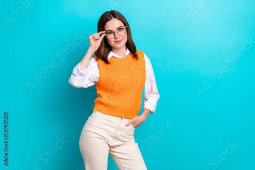 Photo of adorable cute positive woman bob hairstyle orange waistcoat touching glasses hand in pocket isolated on teal color background