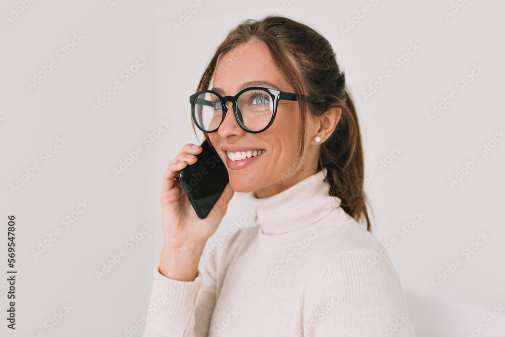 Close up portrait of smiling happy girl in glasses and wonderful smile enjoying talking on smartphone. Happy excited woman talking on the phone over isolated background Close up portrait of smiling happy girl in glasses and wonderful smile enjoying talking on smartphone. Happy excited woman talking on the phone over isolated background