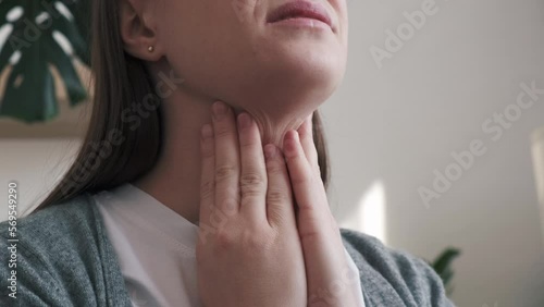 Close up of unhealthy sad young brunette woman holding hands over sore throat feeling discomfort. Painful neck and frowning, thyroid disorders, suffering sore throat, tonsils inflammation concept