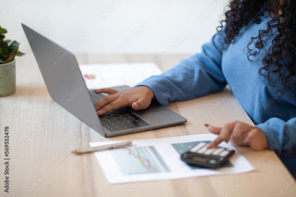 Fototapeta premium Unrecognizable woman accountant using computer and calculator