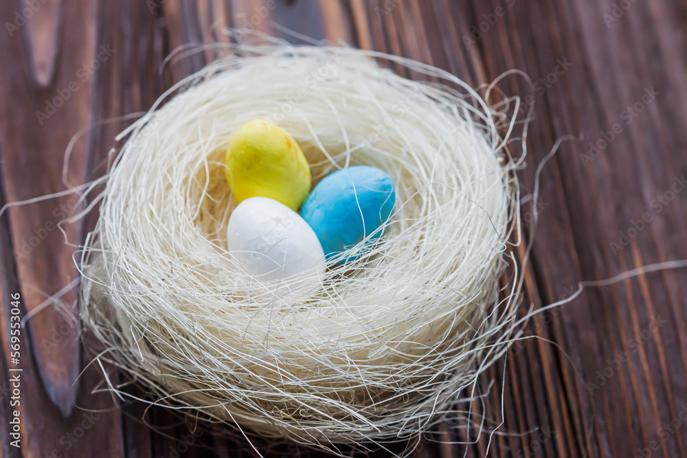 Two eggs of the color of the Ukrainian flag are yellow and blue and a white egg in the nest. The concept of an abandoned home of Ukraine for the Easter holiday. Two eggs of the color of the Ukrainian flag are yellow and blue and a white egg in the nest. The concept of an abandoned home of Ukraine for the Easter holiday.