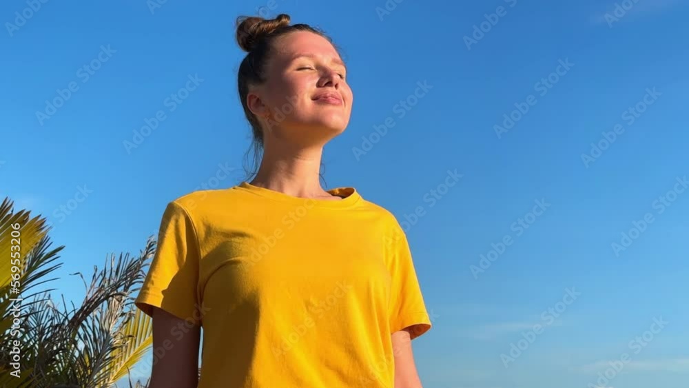 Portrait of happy beautiful young woman, girl is sunbathing, tanning on sun at summer sunny day on natural background with blue sky breathing deep, inhale fresh air, doing breath exercises Portrait of happy beautiful young woman, girl is sunbathing, tanning on sun at summer sunny day on natural background with blue sky breathing deep, inhale fresh air, doing breath exercises