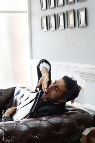 Young mixed-race business man tired from work while on the couch. Exhausted, Yawning and Sleeping