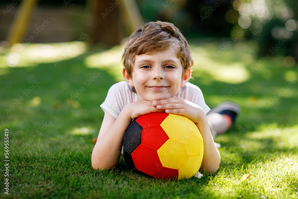Happy active kid boy playing soccer with ball in German flag colors. Healthy child having fun with football game and action outdoors Happy active kid boy playing soccer with ball in German flag colors. Healthy child having fun with football game and action outdoors