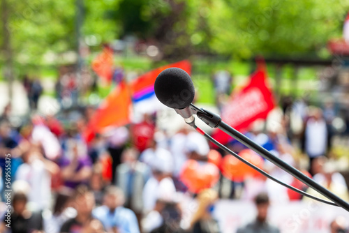 Protest, public demonstration or pension reform strike, focus on microphone, blurred crowd of people in the background