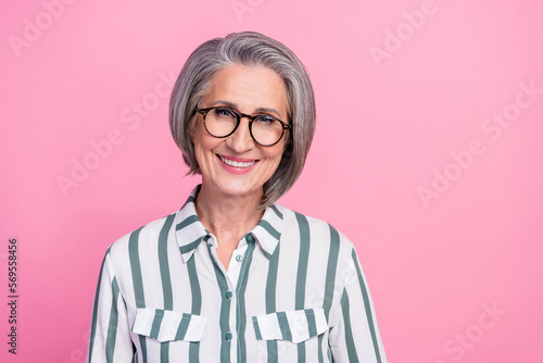 Photo of old pensioner business lady wear grey hair cheerful smiling wear striped shirt wear glasses enjoy her job isolated on pink color background