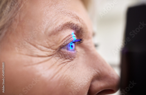Eye exam, vision or laser test for an old woman with a machine at optometry consultation for retina problem. Senior, patient or client with medical health insurance checking eyesight at optician