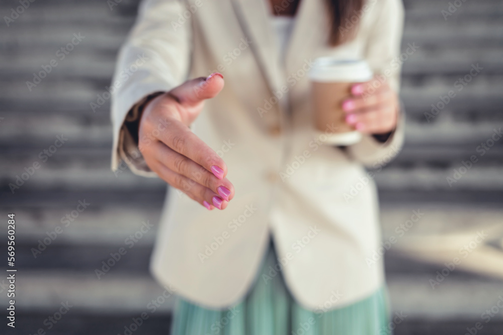 Closeup shot of a businesswoman gesturing for a handshake in the city.