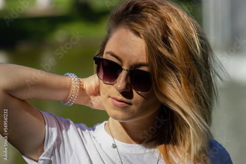 Beautiful young girl with a bob hairstyle in sunglasses on the background of the lake with a fountain