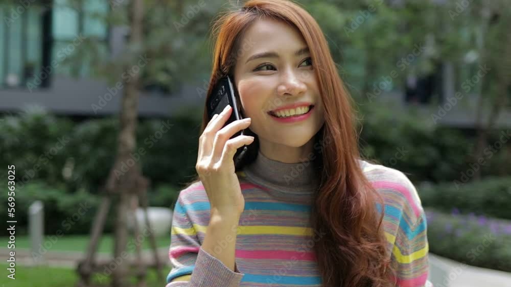 Cheerful Asian beautiful woman happy She walks on the phone talking in the outdoor garden of her modern apartment. Housing concept. city living Cheerful Asian beautiful woman happy She walks on the phone talking in the outdoor garden of her modern apartment. Housing concept. city living
