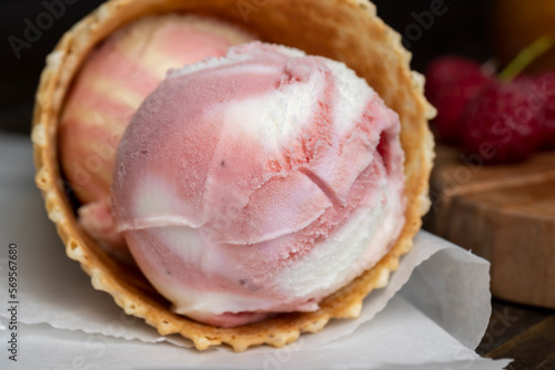 Waffle cone with white pink cream ice cream and raspberries