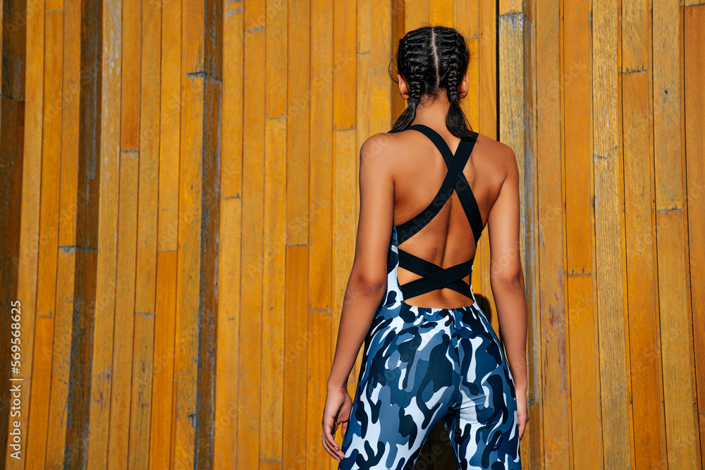 Fototapeta premium sports girl on a wooden wall background with his back to the frame medium shot don't look into the frame