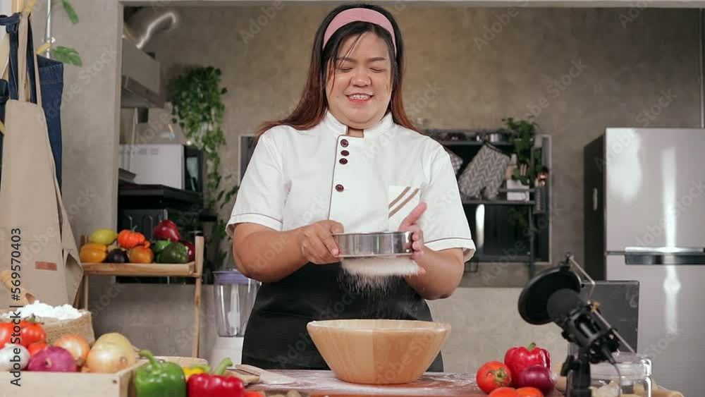 Fat woman chef sifting flour through a sieve Start making pizza the traditional way. Blogger teaches how to make homemade Italian pizza in the kitchen via video camera. Live online on social media. Fat woman chef sifting flour through a sieve Start making pizza the traditional way. Blogger teaches how to make homemade Italian pizza in the kitchen via video camera. Live online on social media.
