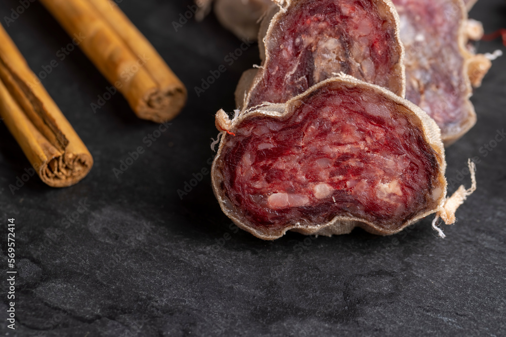 Unpeeled sliced pork salami with spices