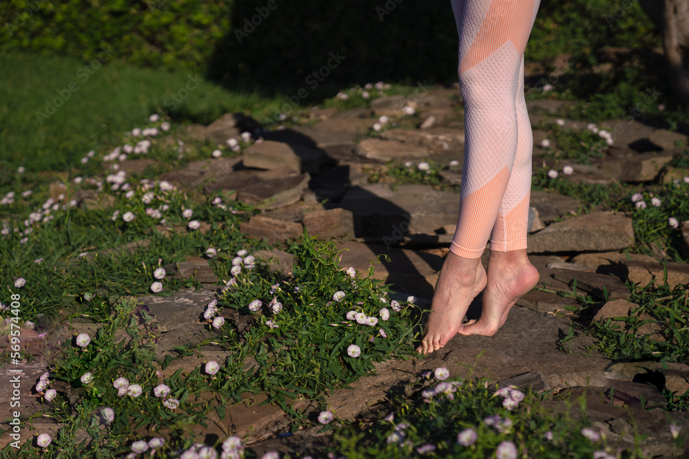 Fototapeta premium A girl is engaged in yoga on the street, in a pink tracksuit does various exercises and yoga poses