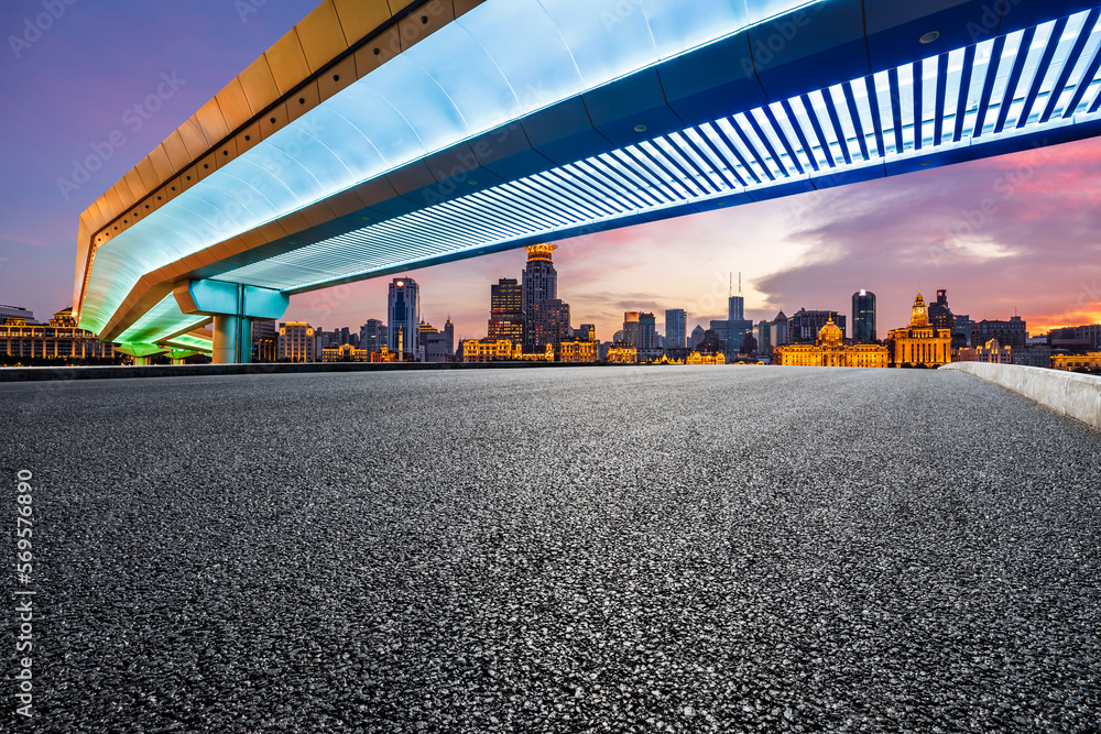 Asphalt road and bridge with city skyline at sunset in Shanghai, China.
