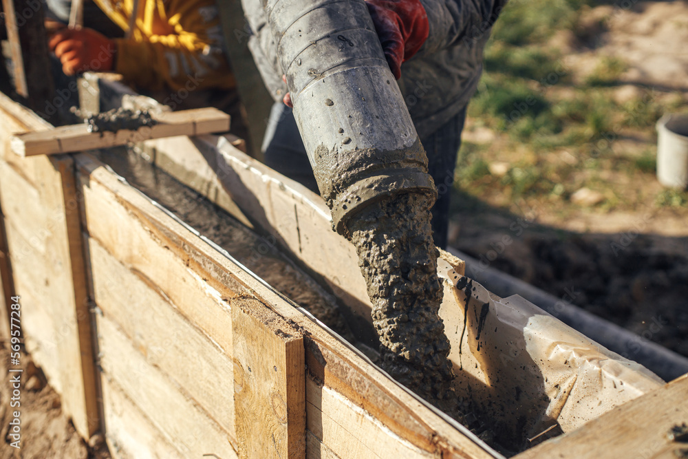 Workers Pouring Concrete In Formwork For Foundation Construction Site workers-pouring-concrete-in-formwork-for-foundation-construction-site
