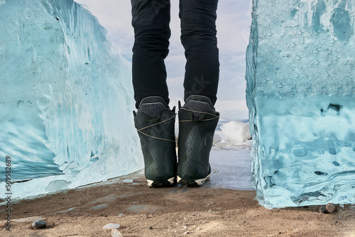 The traveler stands on the beach among the ice rocks of the Arctic