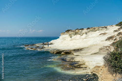 Fishermen are fishing on the seashore. Coast of white stones.