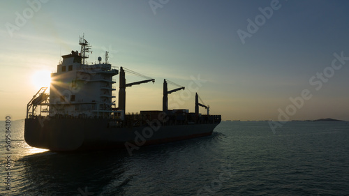 corgo ship container in silhouette and over the sunlight at evening in open sea. aerial view