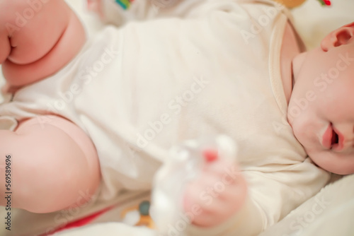 The tummy of a newborn baby dressed in a white bodysuit.