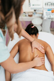 Beautiful young adult brunette receiving professional relaxation massage treatment at beauty spa salon.