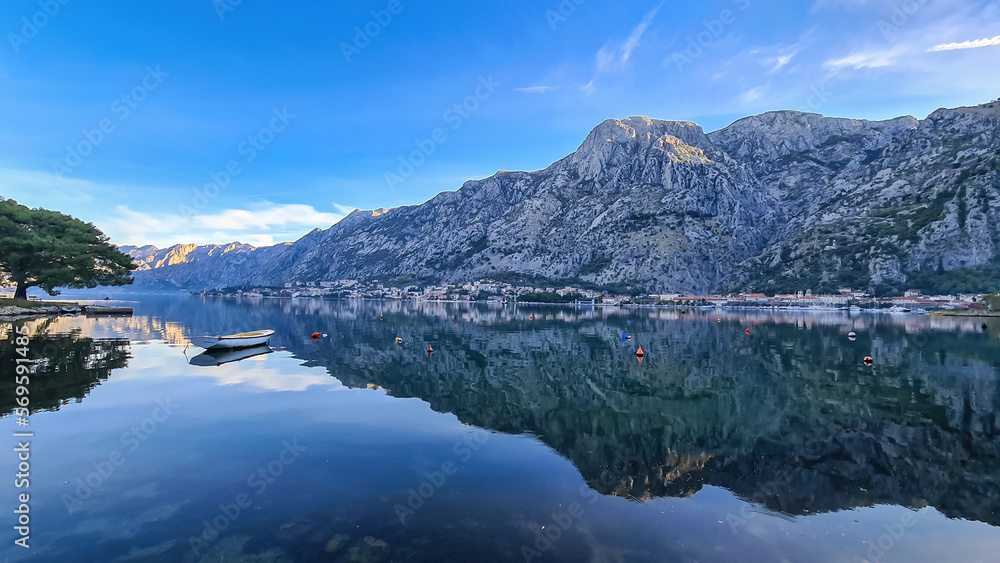 Panoramic view of bay of Kotor on sunny summer day at Adriatic Mediterranean Sea, Montenegro, Balkans, Europe. Fjord winding along coastal towns. Lovcen mountains are reflected in the water surface