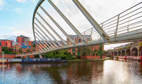 Amazing rainbow over the waterway canal area with a narrowboat on the foreground modern bridge, Castlefield district - Manchester, UK