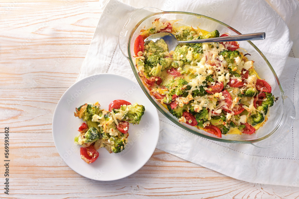 Casserole from vegetables with broccoli, tomatoes, onions, feta and cheese, healthy low carb meal on a light wooden table, copy space, high angle view from above Casserole from vegetables with broccoli, tomatoes, onions, feta and cheese, healthy low carb meal on a light wooden table, copy space, high angle view from above