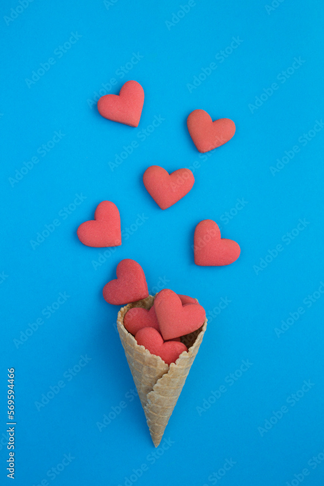 Ice cream cone with heart shaped cookies on the blue background. Top view. Close-up. Ice cream cone with heart shaped cookies on the blue background. Top view. Close-up.