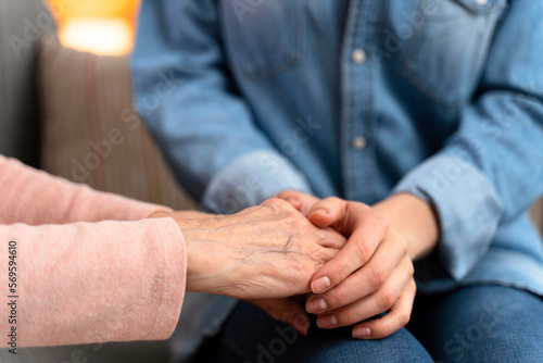 Mature female in elderly care facility gets help from hospital personnel nurse. Senior woman, aged wrinkled skin and hands of her care giver. Grand mother everyday life concept