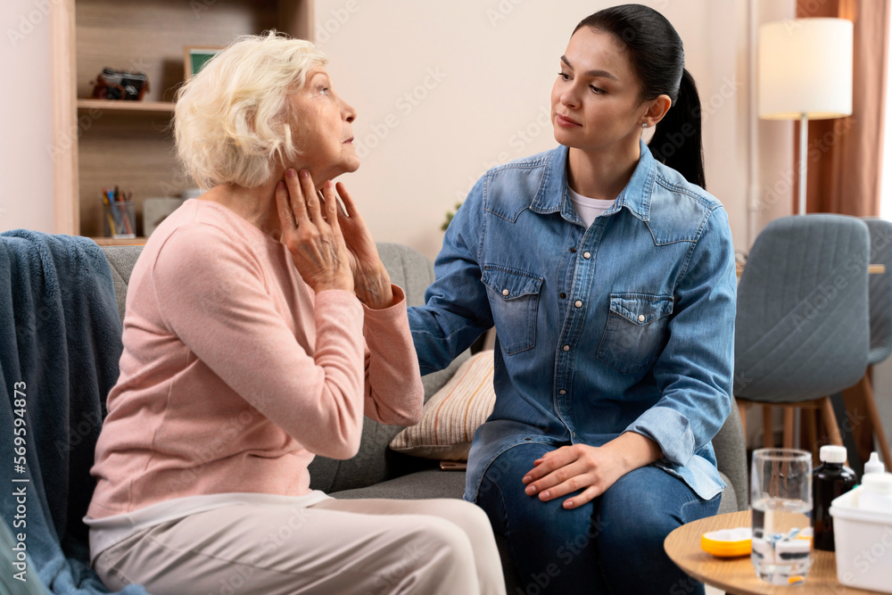 Caring nurse examining ill senior woman at home. Take care of elderly people concept. Stock photo