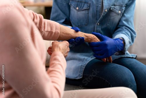 Cropped view of the nurse measuring heartbeat of senior woman at home. Young practitioner taking care of the elderly woman