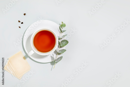 Cup of tea. Eco friendly still life with cup of tea, eucalyptus sprig and paper tea bags on blue background. Concept of organic tea and healthy natural drink. Flat lay, copy space