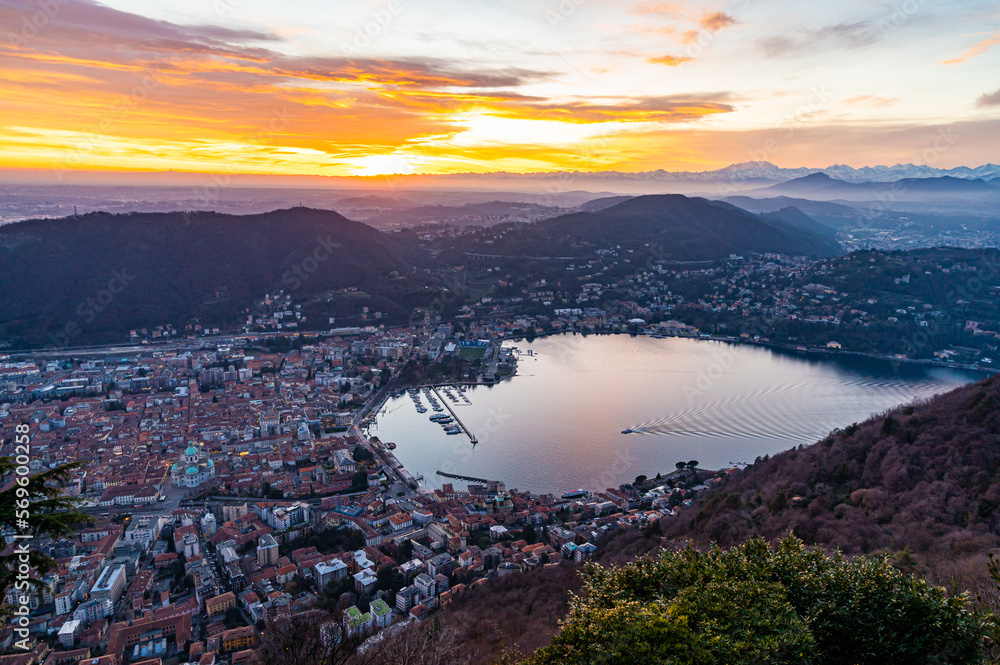 The city of Como, the lakefront and the lake, photographed from Brunate, at dusk, and all the mountains in the background.
