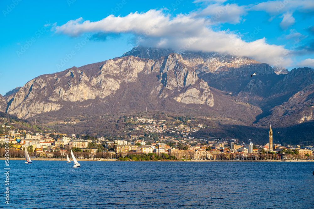 The city of Lecco, with its lakefront and its buildings, photographed in the evening.
