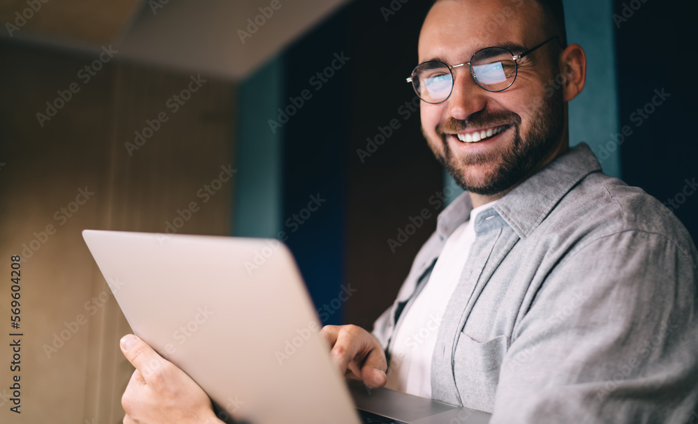 Smiling man in eyeglasses using computer while working Smiling man in eyeglasses using computer while working