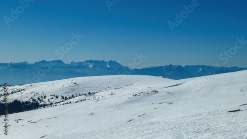 Panoramic view on summit cross of mountain peak Grosser Sauofen in winter on Saualpe, Lavanttal Alps, Carinthia, Austria, Europe. Snowcapped mountain ranges of Karawanks and Kamnik Savinja Alps © Chris