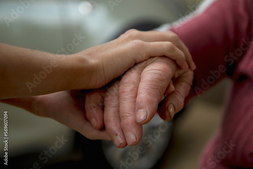 Fototapeta Naklejka Na Ścianę i Meble -  The hands of a young girl hold the bitches of her elderly grandmother. The concept of love and care for the elderly, respect within the family and acceptance of old age