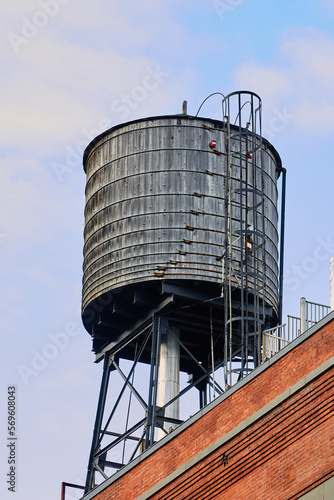 Grey Water Tower with Ladder on Red Brick Building in NYC