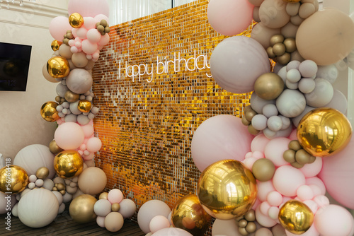 A large festive photo zone for a birthday, decorated with gold sequins, pink, gray and gold balloons of different sizes. Celebrating concept